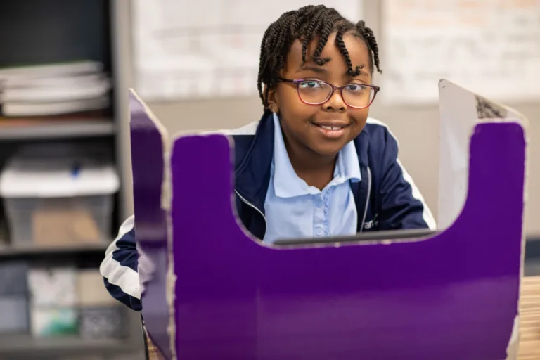 A child in a classroom with a purple divider on their desk
