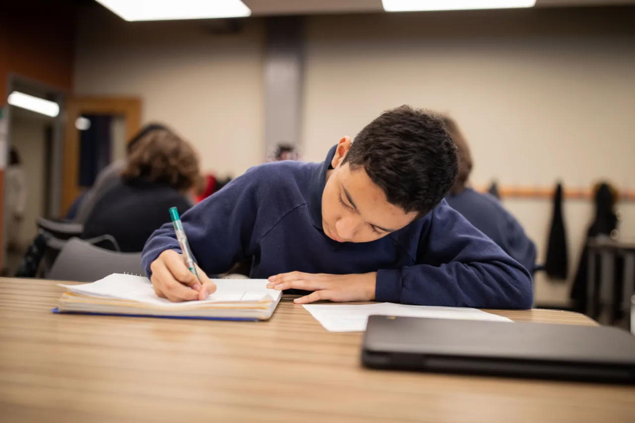 A student taking notes in a notebook