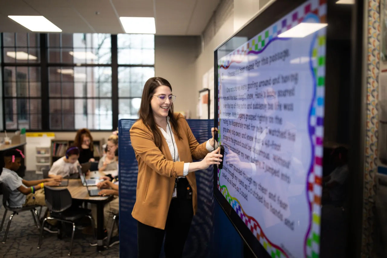 A teacher presenting notes to a classroom on a large television screen