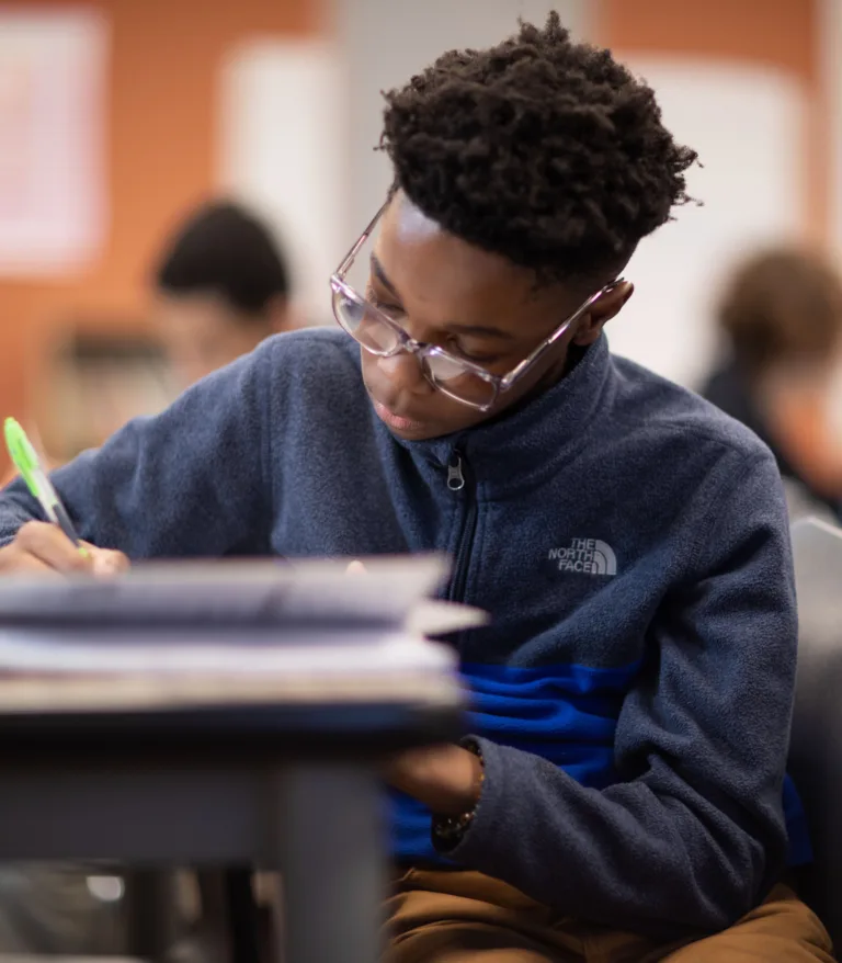 A student taking notes at their desk