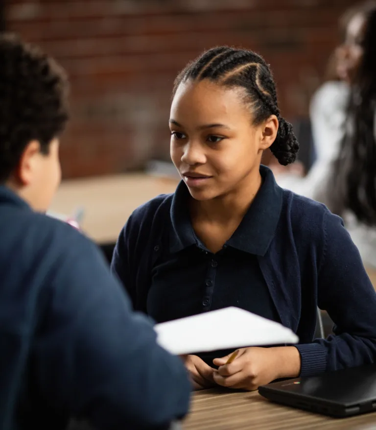 Two students at a desk talking