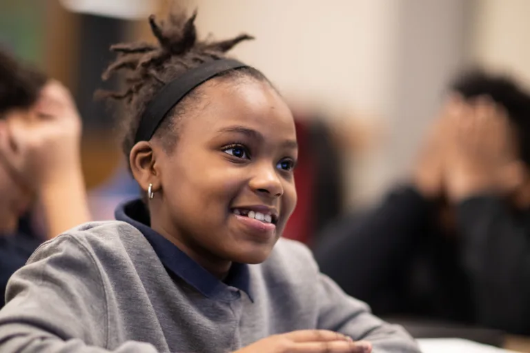 A smiling student in a classroom at her desk