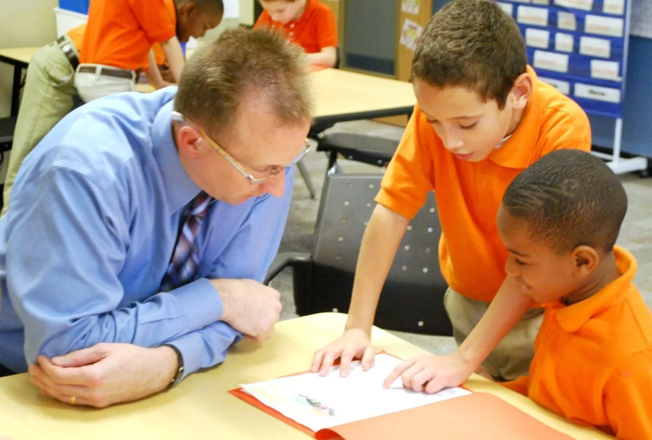 A teacher assisting two students with an assignment