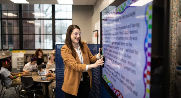A teacher presenting notes to a classroom on a large television screen
